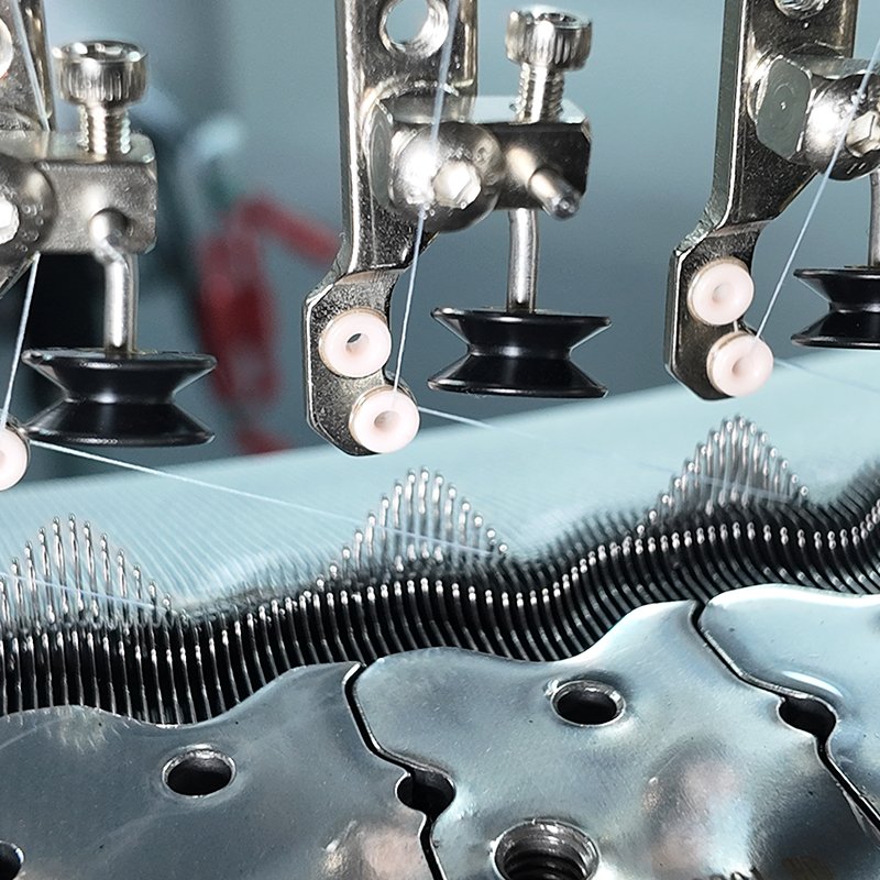 Macro view of knitting needles, sinkers, and smooth yarn threading mechanism on open width circular machine